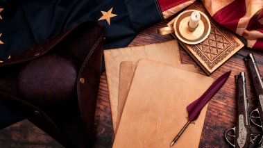 Aged papers on a table with a pen and American flag