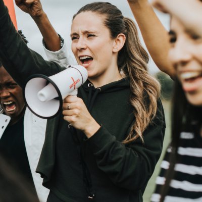 Peaceful protest with young woman speaking into a megaphone.