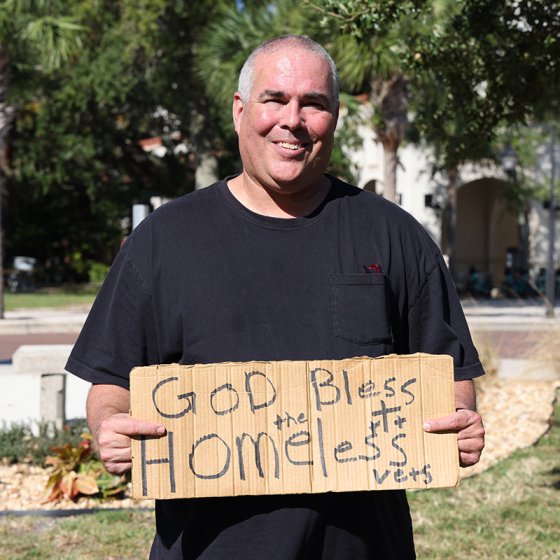 FIRE plaintiff Jeff Gray holds a sign reading "God bless homeless vets"