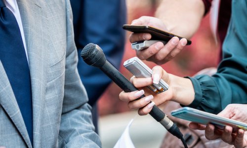 Journalists with microphones interviewing formal dressed politician or businessman.