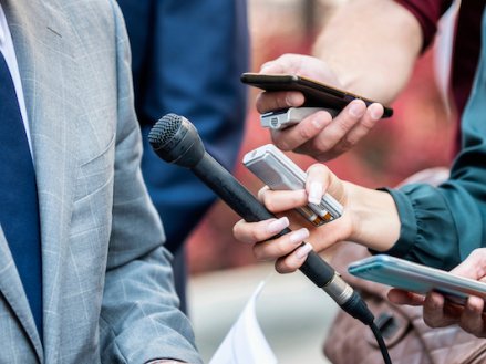 Journalists with microphones interviewing formal dressed politician or businessman.