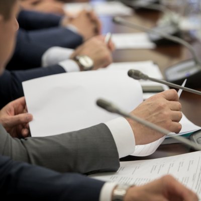 politician sitting by table with his hands over document during political summit or conference