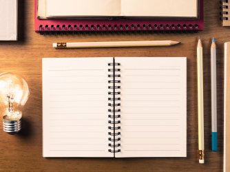 Notebook, pencils, and lightbulb on a desk