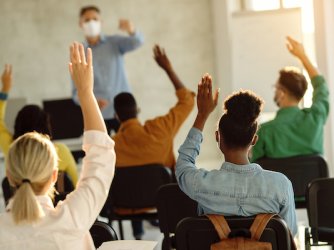 Students raising hands in a classroom - CREDIT Drazen Zigic Shutterstock