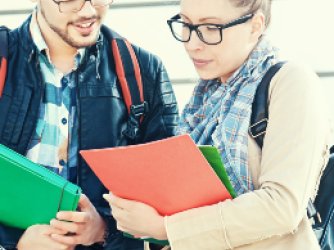 two college students standing and comparing notes on brightly colored file folders